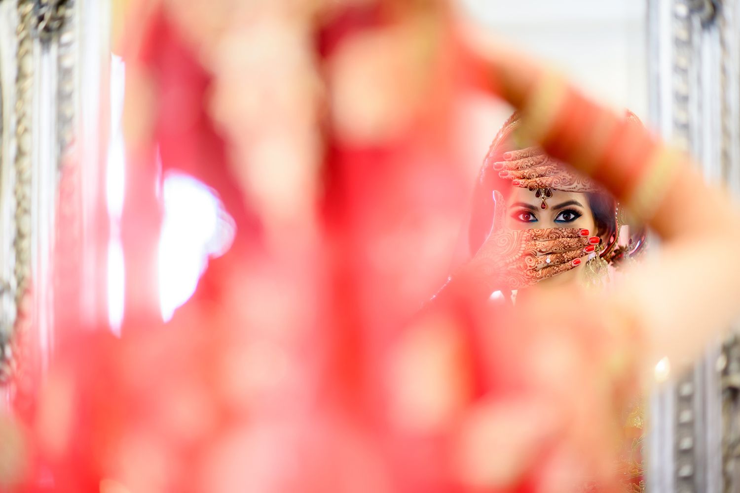 Creative wedding photography shot showing reflection in decorative mirror with bokeh effect.