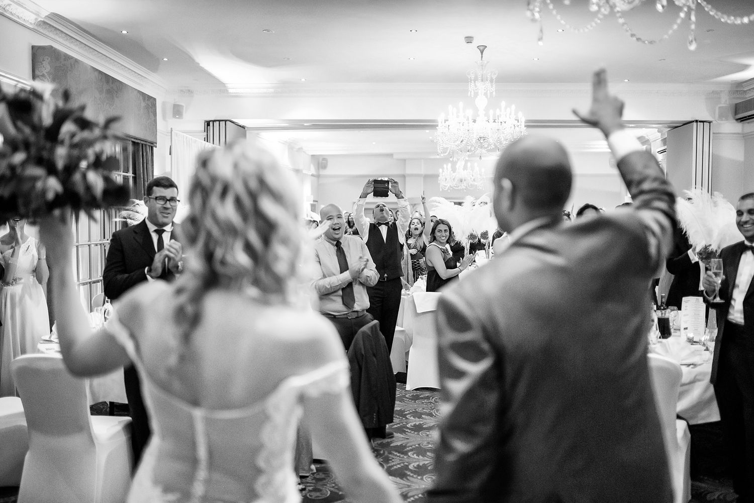 Black and white photo of wedding reception dance floor with chandelier overhead.