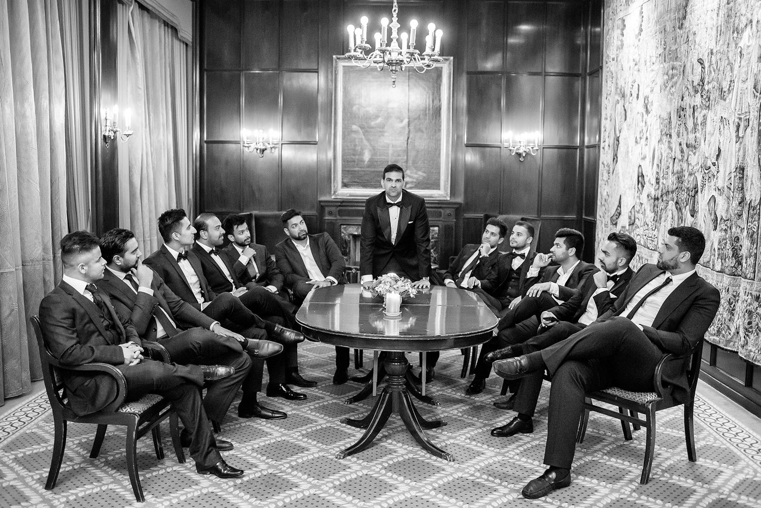 Black and white photograph of guests seated in rows at formal event with chandelier lighting.