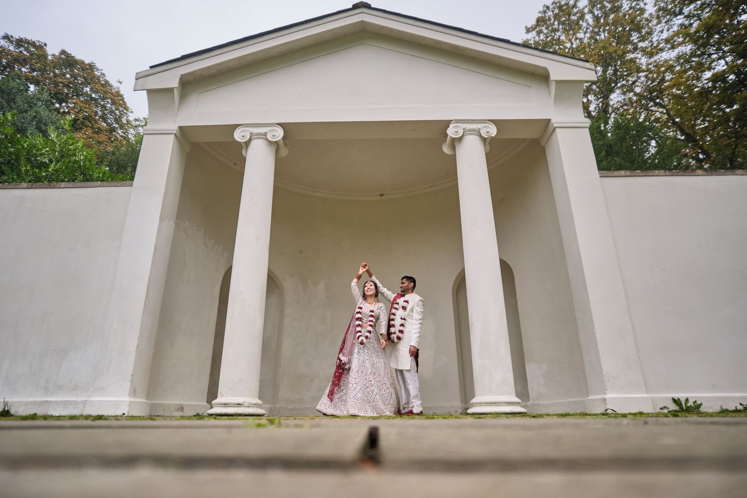 White architectural structure with classical columns and pillars against a cloudy sky.