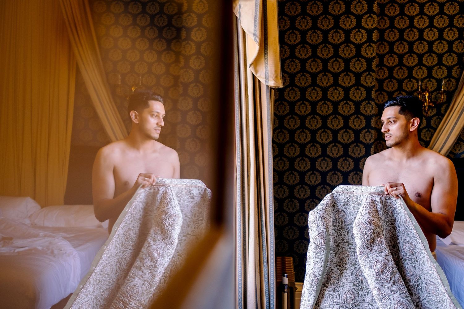 Artistic mirror reflection shot of a person wrapped in white bedding in an elegant hotel room setting.
