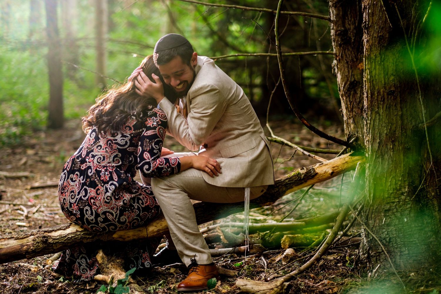 Couple posing for romantic forest photos among tall pine trees and natural greenery.