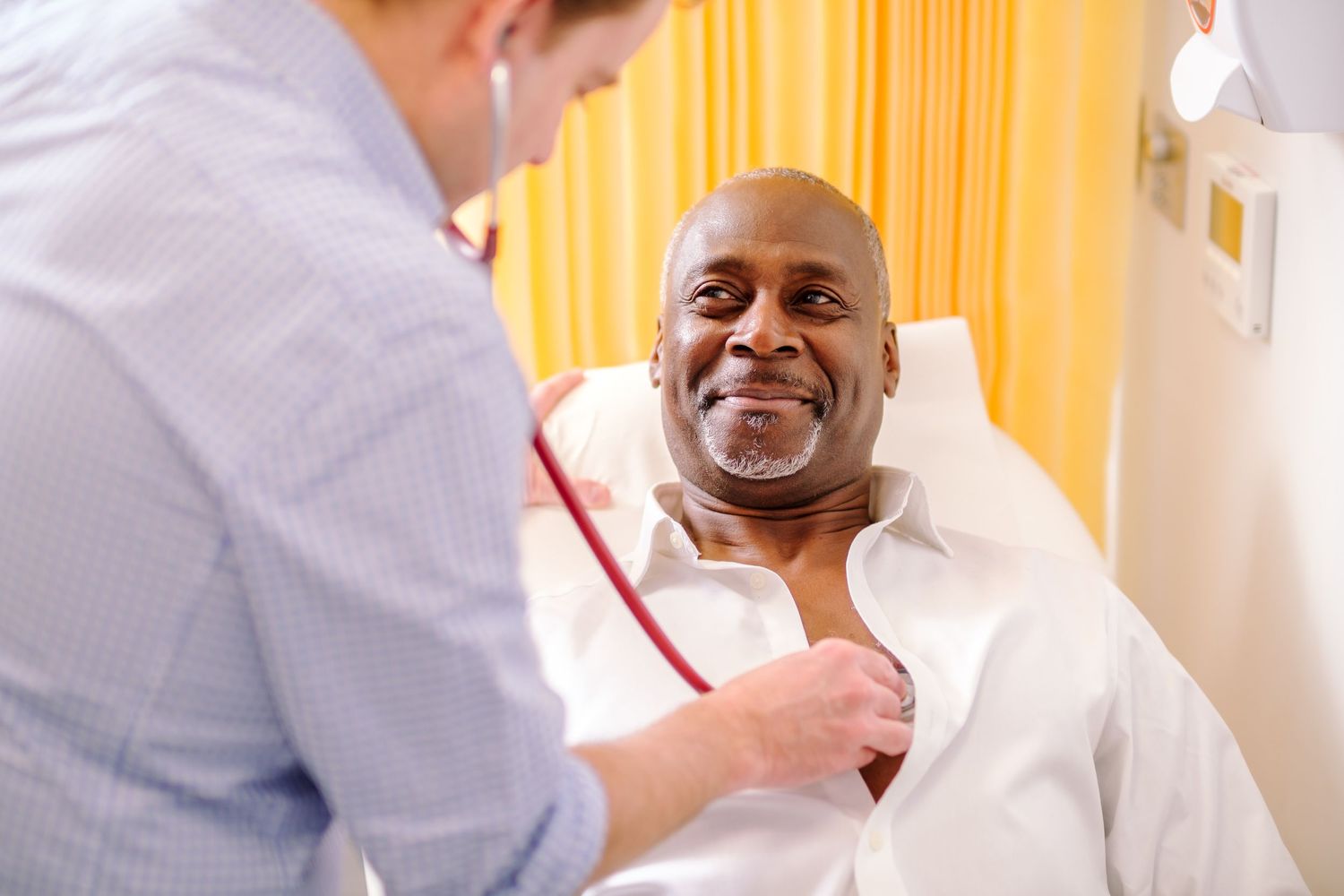 Healthcare worker in white coat interacting with patient during medical consultation.