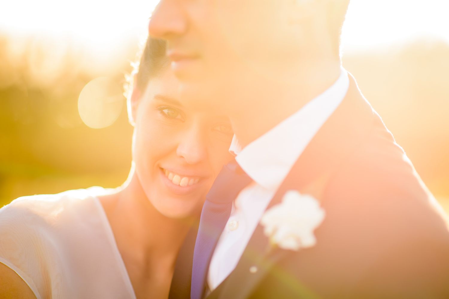 Golden sunset light illuminates a romantic outdoor wedding scene.
