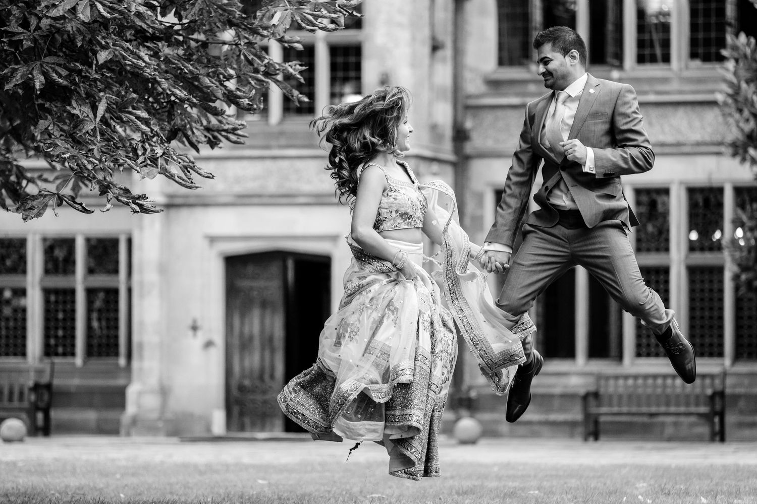 Wedding couple playfully poses in front of historic stone building architecture.