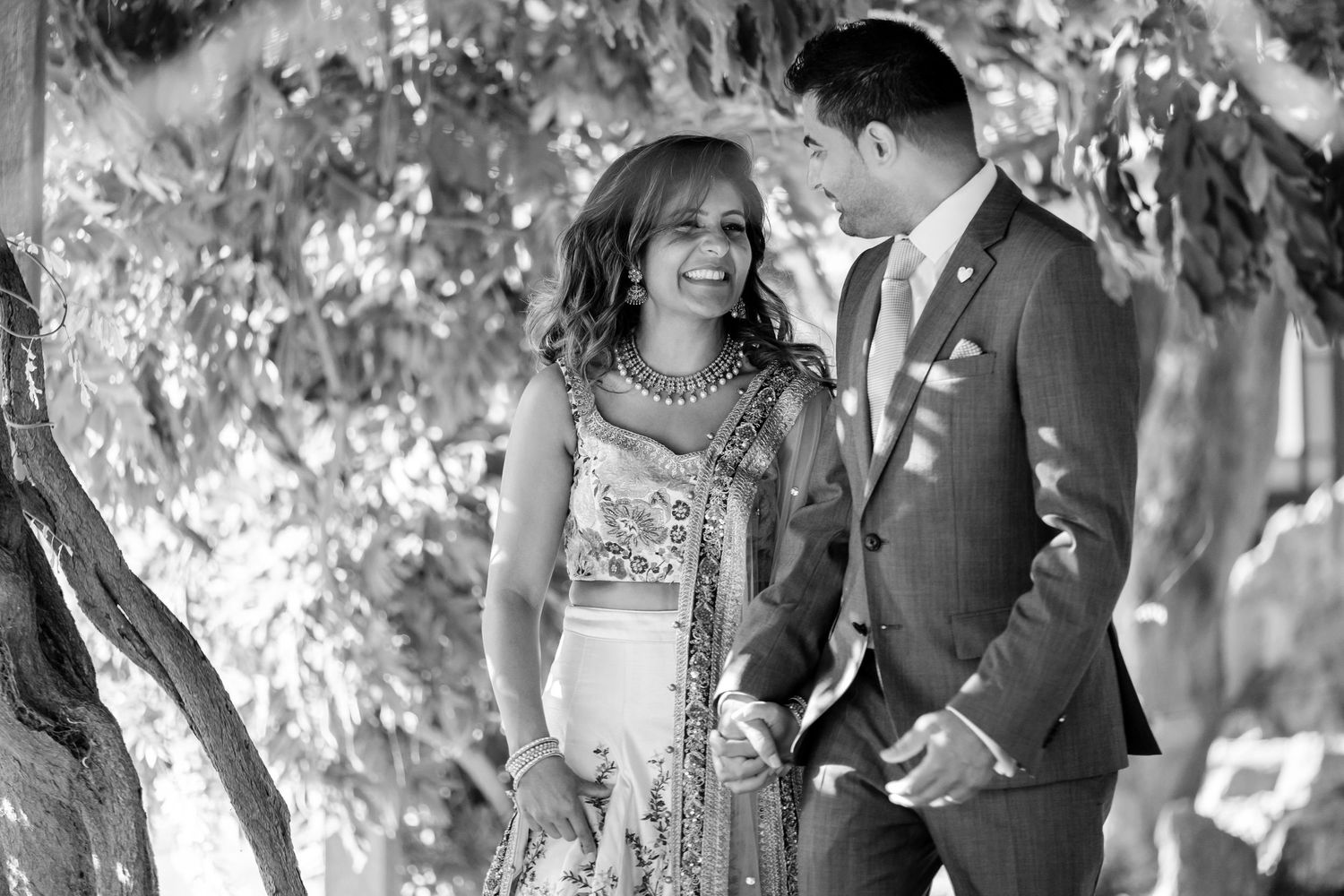 A romantic wedding photoshoot outdoors in a park with natural lighting and trees in the background.
