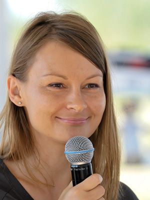 Speaker holds microphone while presenting with natural smile.