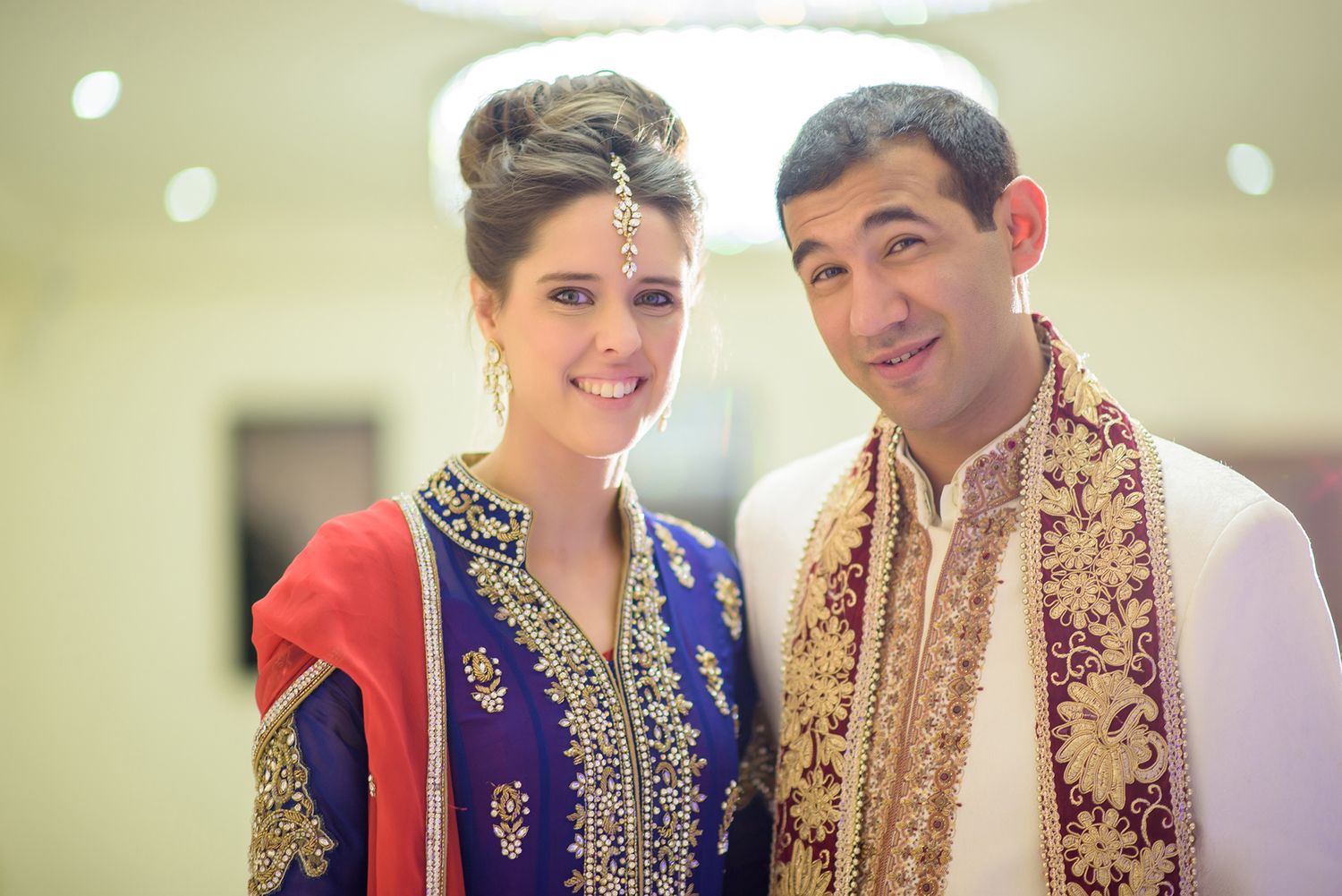 A couple in traditional Indian wedding attire poses together in a series of celebratory portraits.