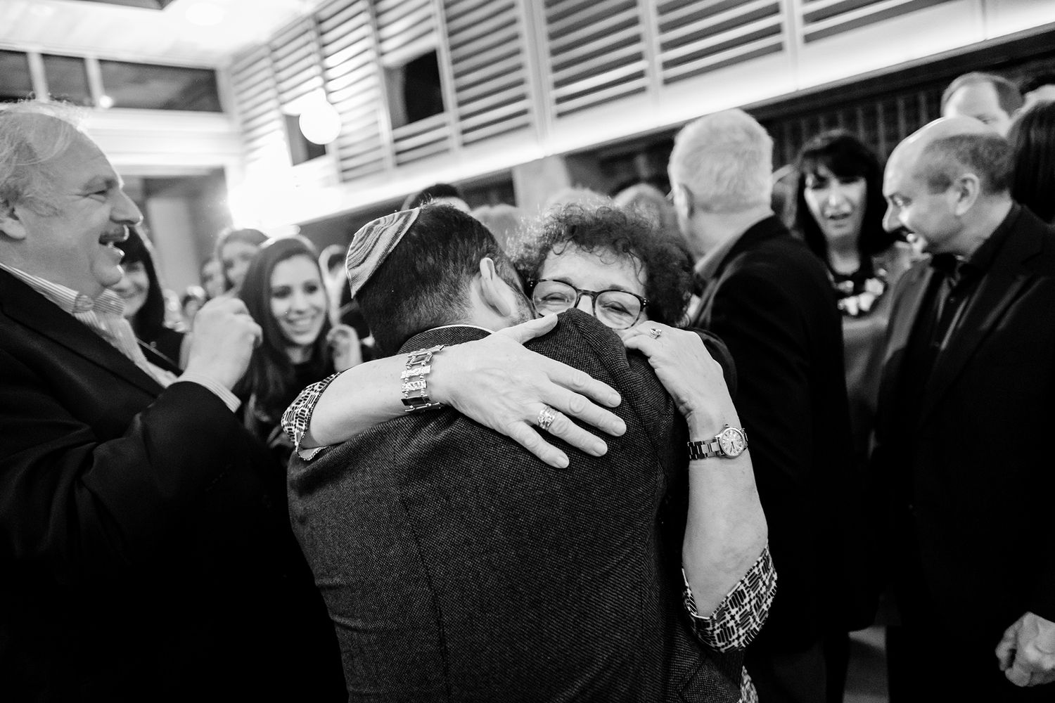 Black and white photo of guests celebrating at a lively party, embracing and sharing joyful moments together.