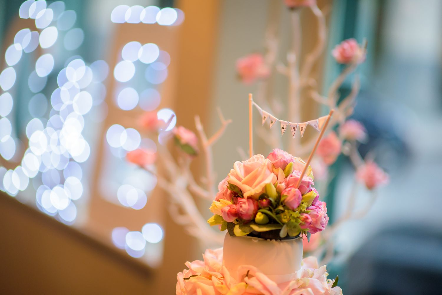 Romantic bokeh lights and pink floral decorations at wedding venue.