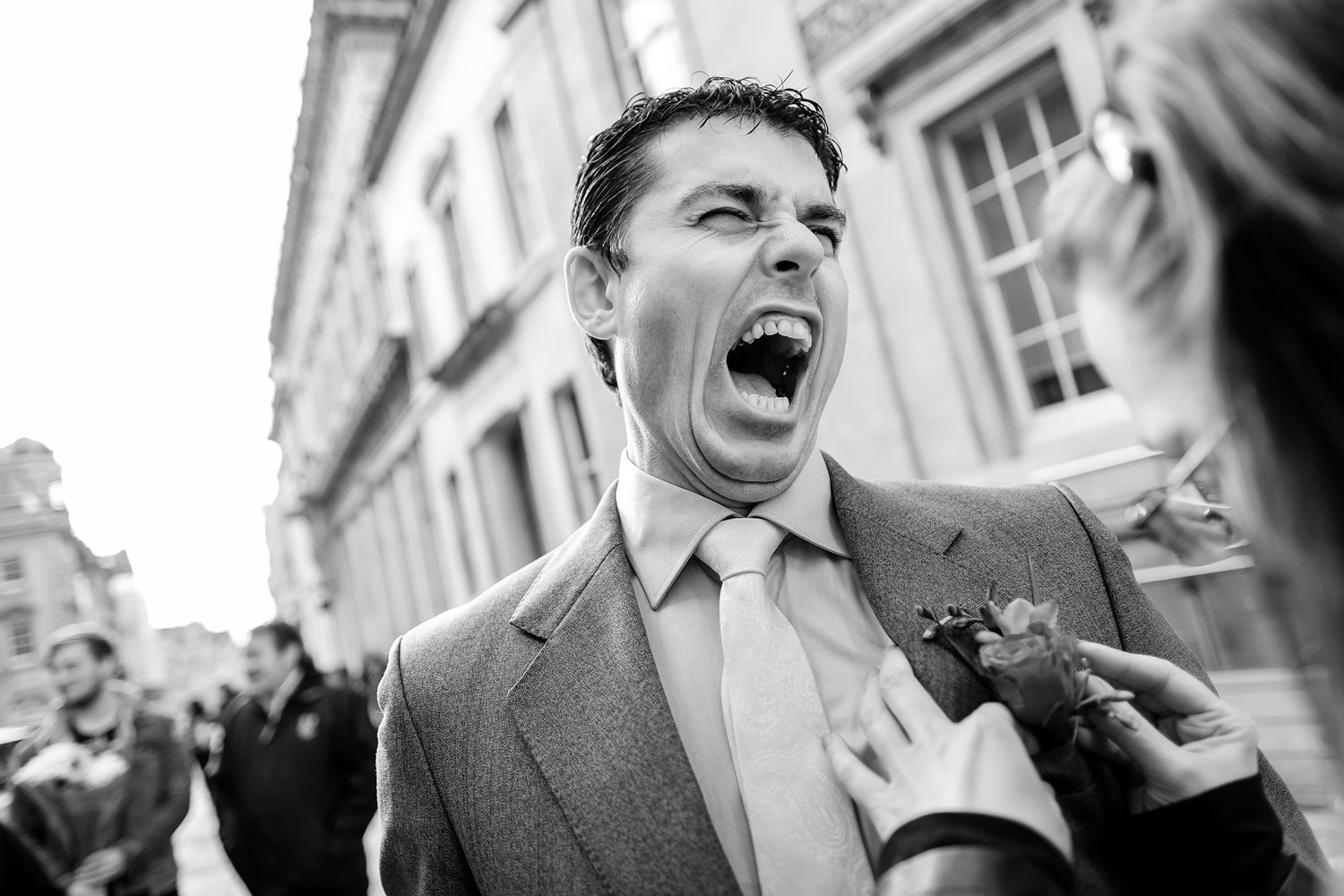 Black and white candid photo capturing an energetic wedding moment outdoors.