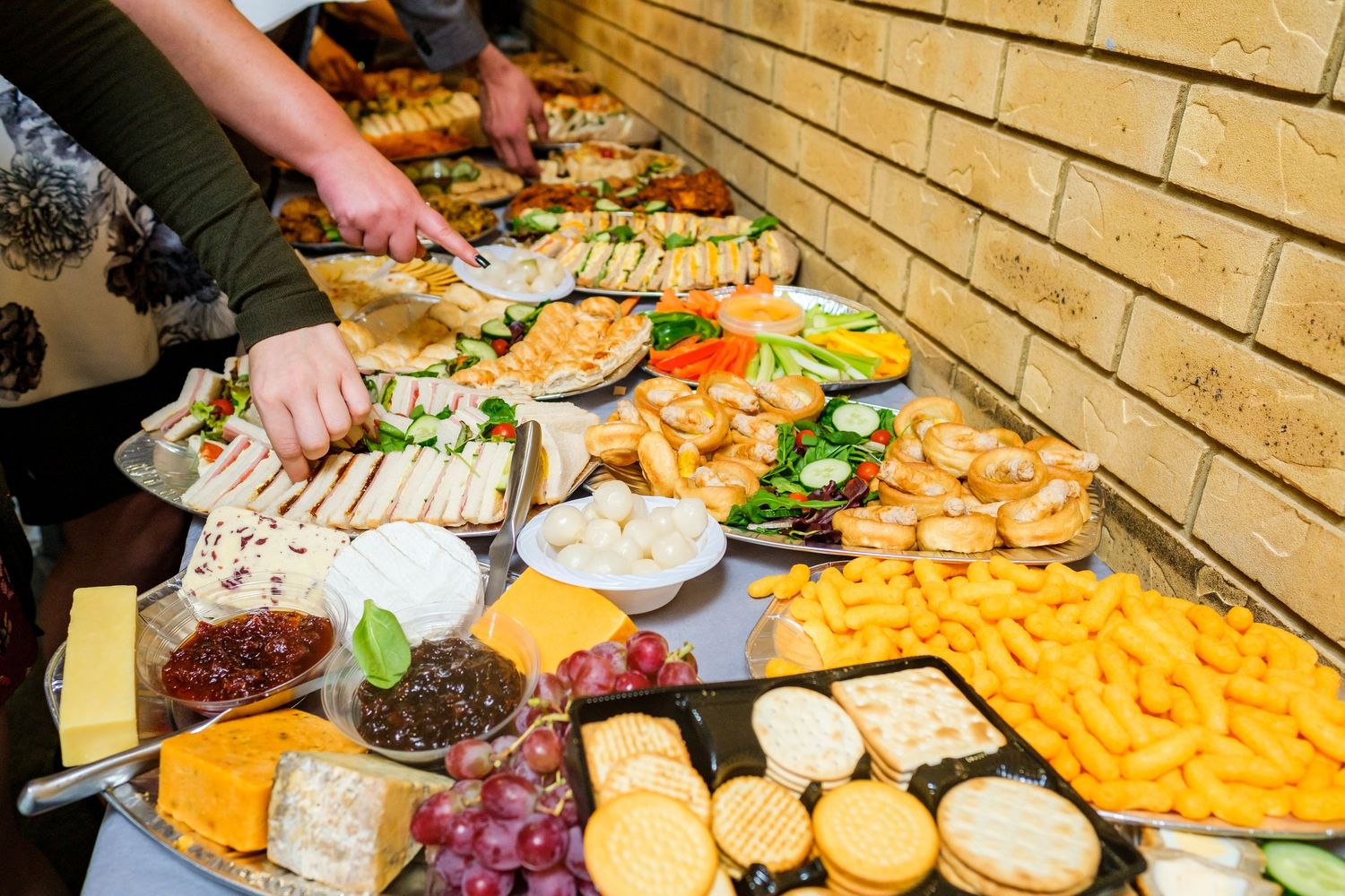 Elegant cheese and appetizer display with various fruits and crackers on wooden table.
