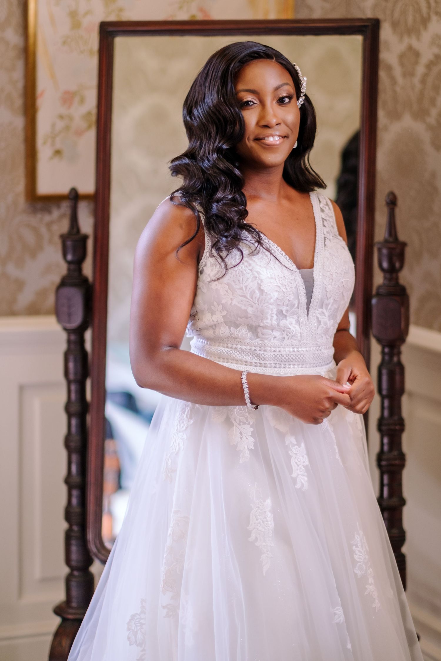 Beautiful bride poses in an elegant white lace wedding dress against an ornate interior backdrop.