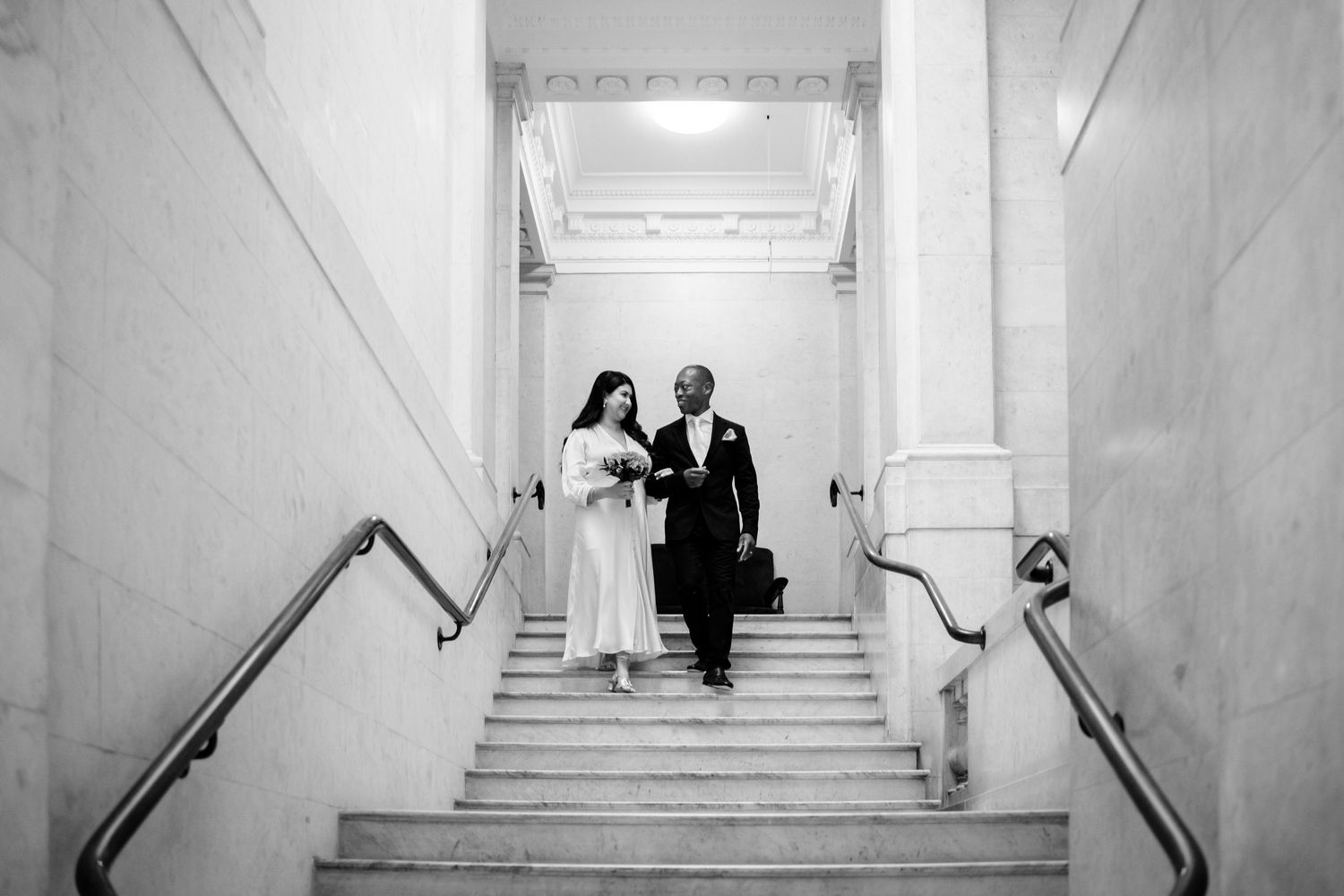 Black and white panoramic view of a grand marble staircase in a historic building.