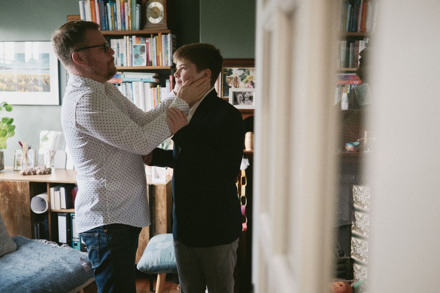 Wedding guests enjoy drinks and conversation in a cozy indoor setting with bookshelves in the background.