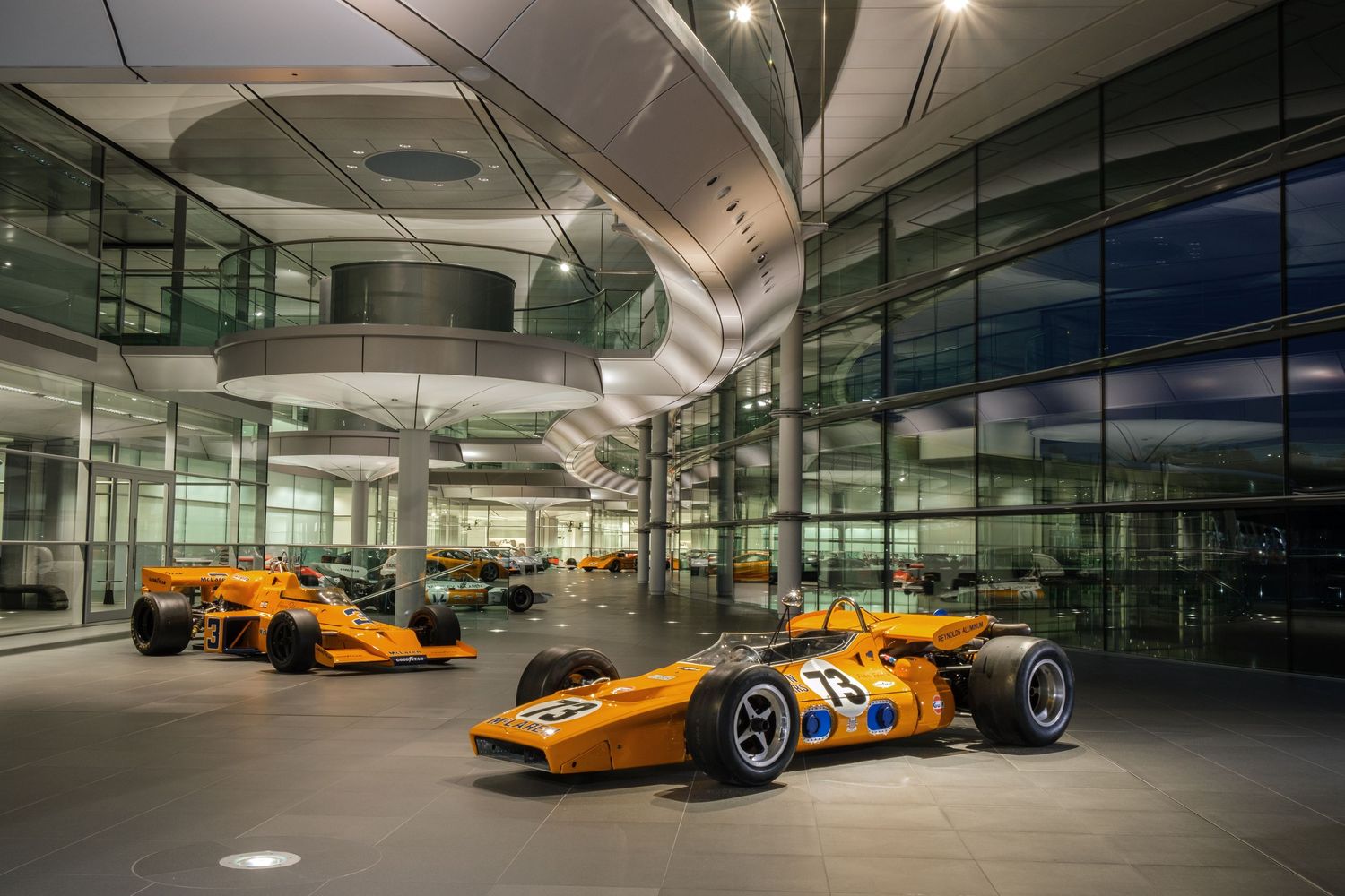 Exhibition space displaying orange McLaren Formula 1 race cars in modern showroom.