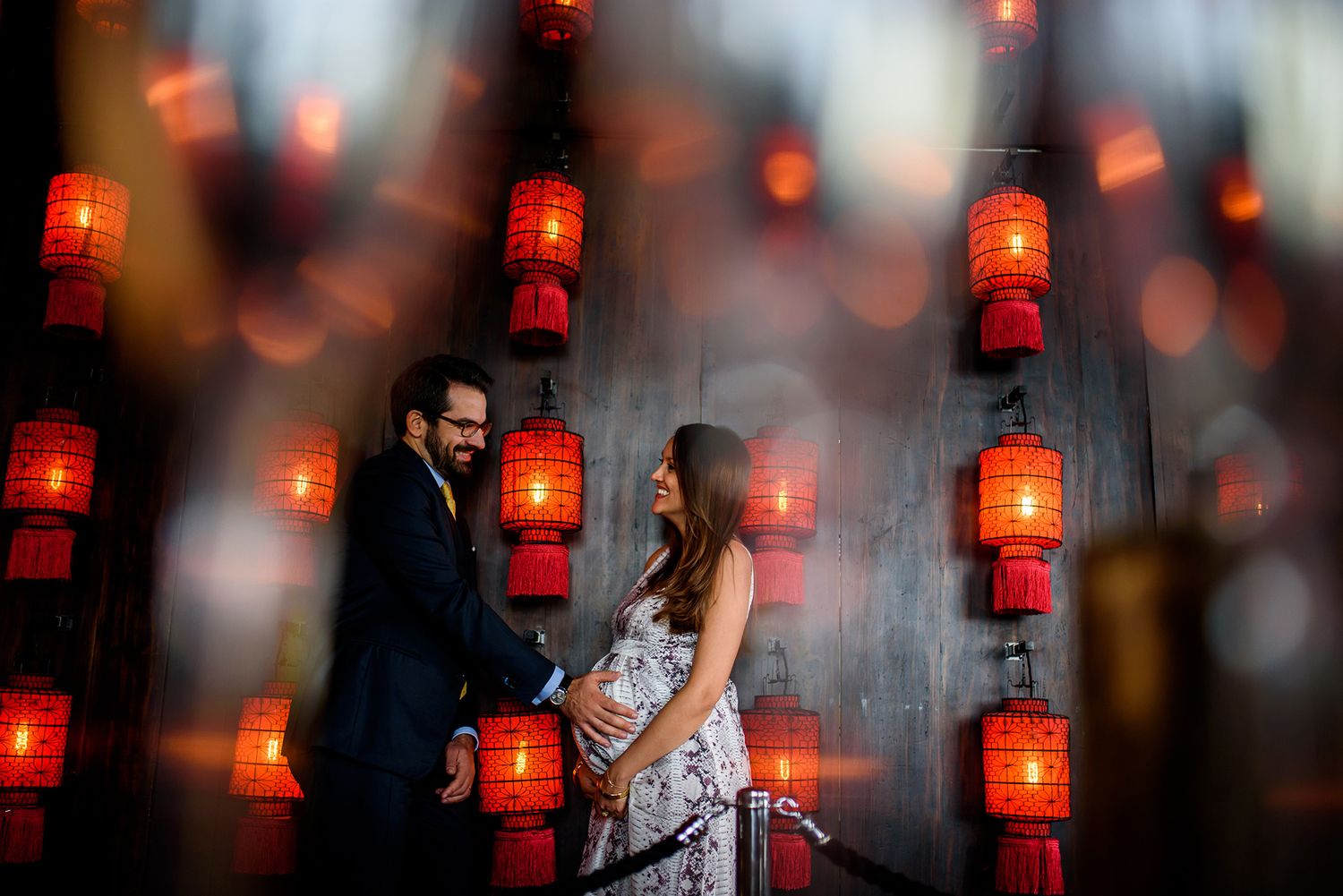Artistic portrait with bokeh effect from red lanterns in background.