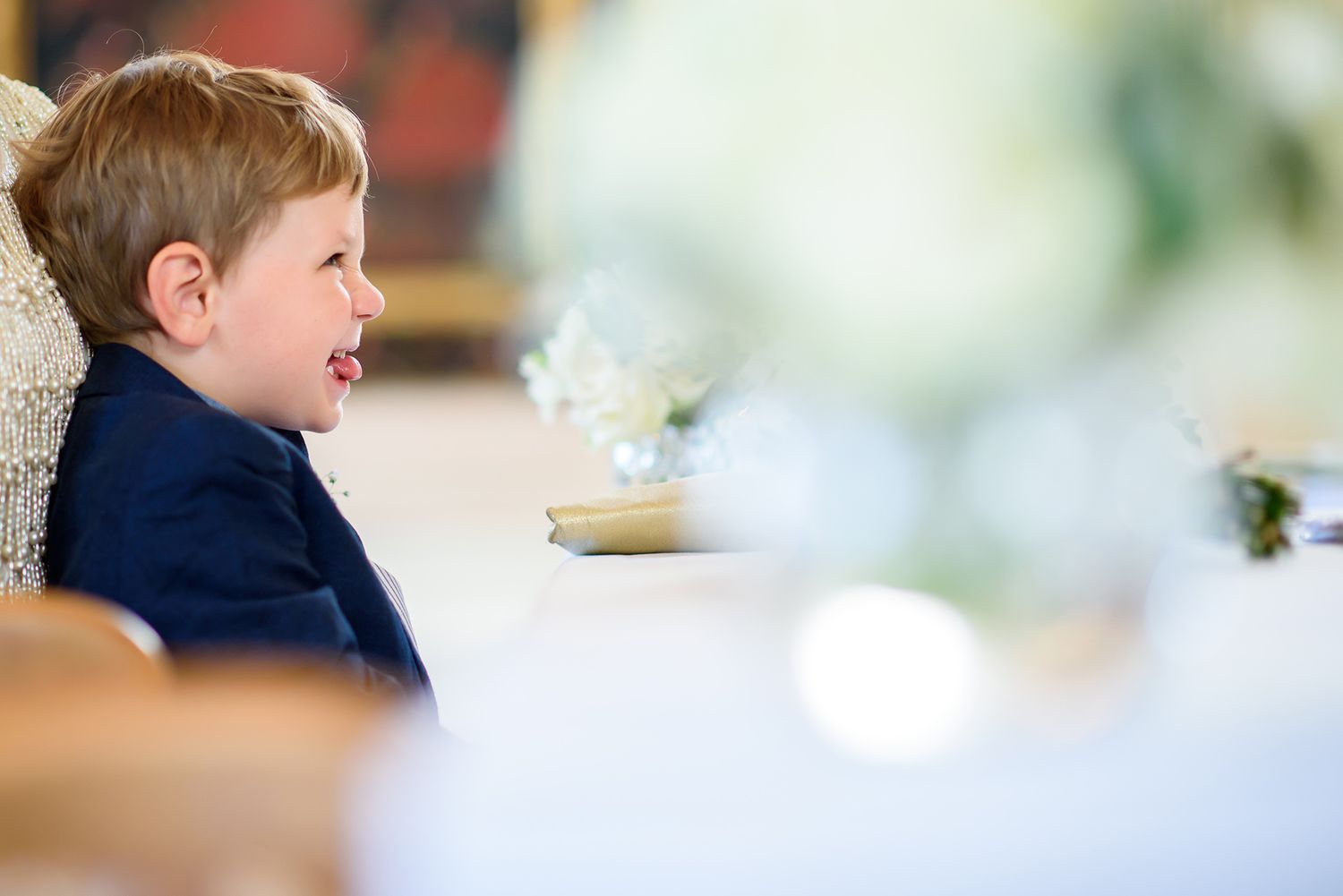 Young attendee in a navy blue suit smiles while enjoying a wedding celebration.