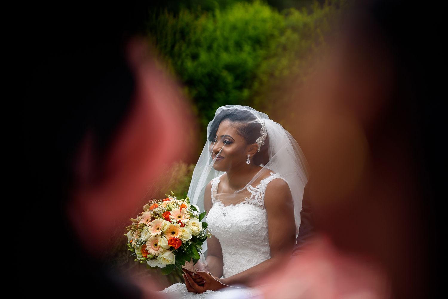 Elegant bride holds a colorful bouquet of flowers during an outdoor wedding ceremony.