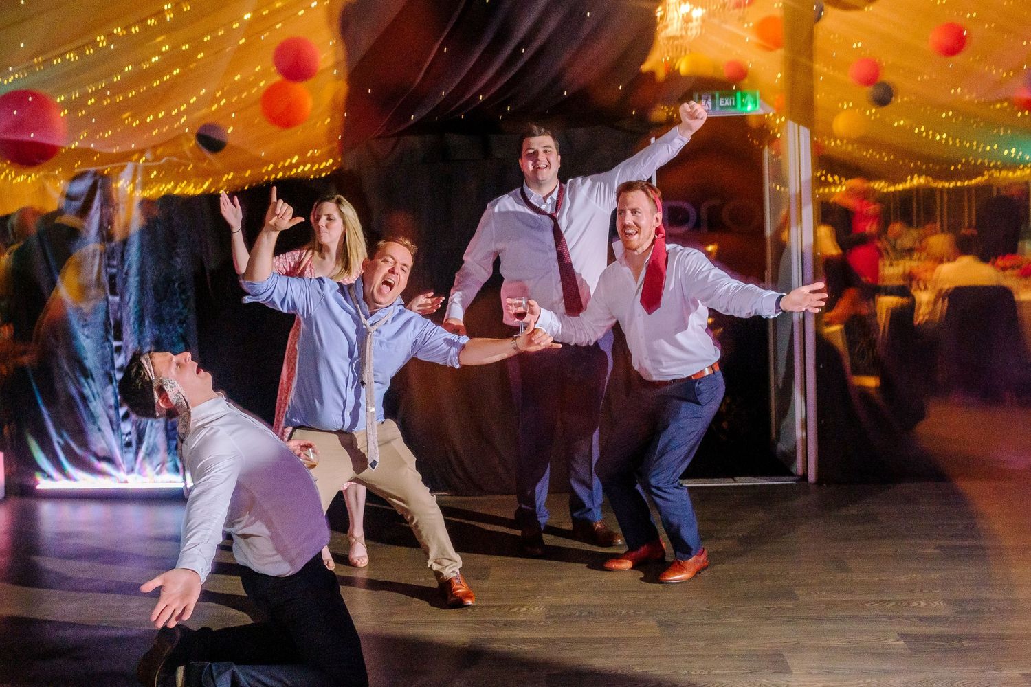 Wedding reception dance floor filled with energetic guests under warm string lights.