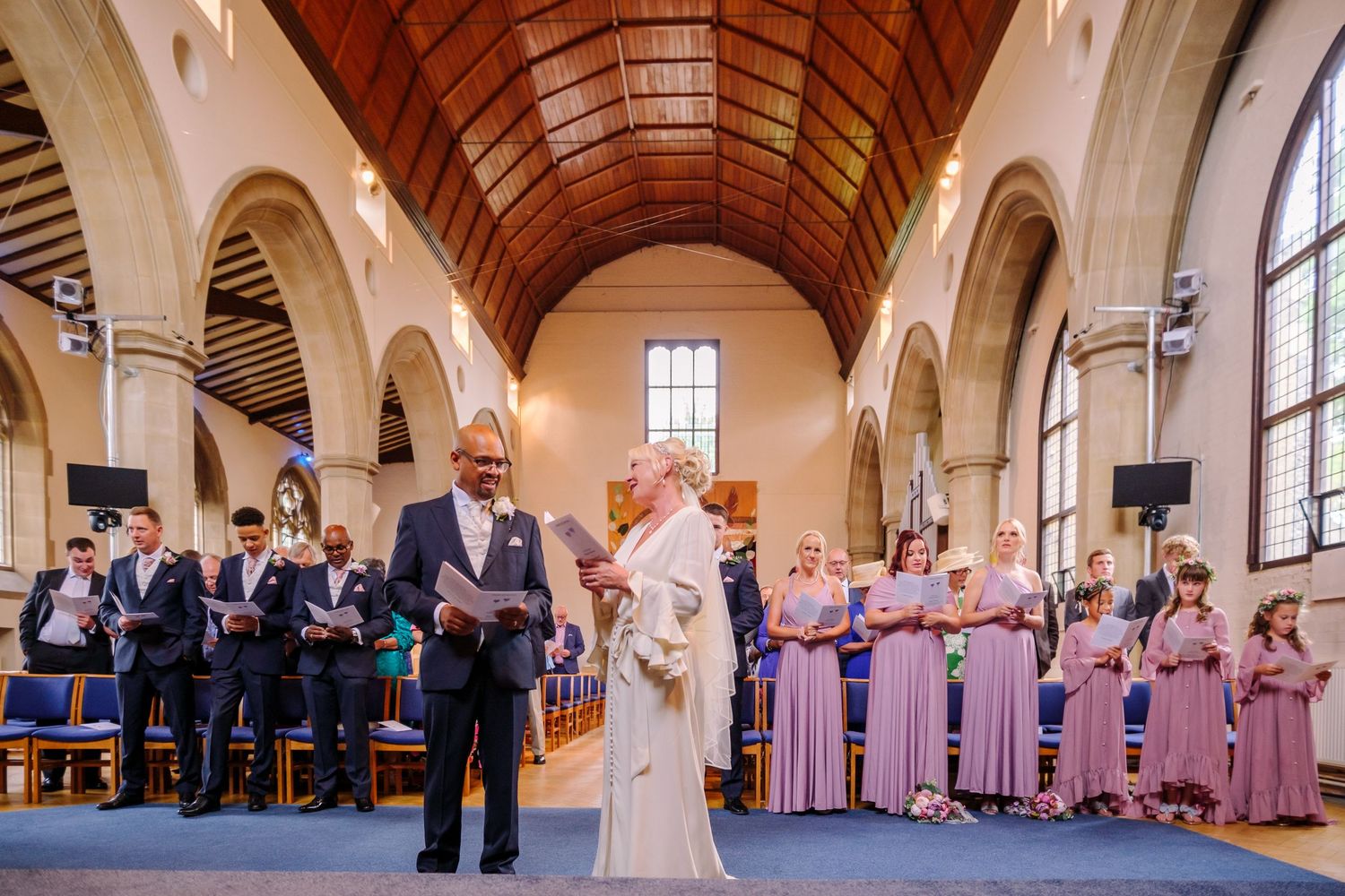 Wedding ceremony in a grand church interior with arched ceilings and stained glass windows.