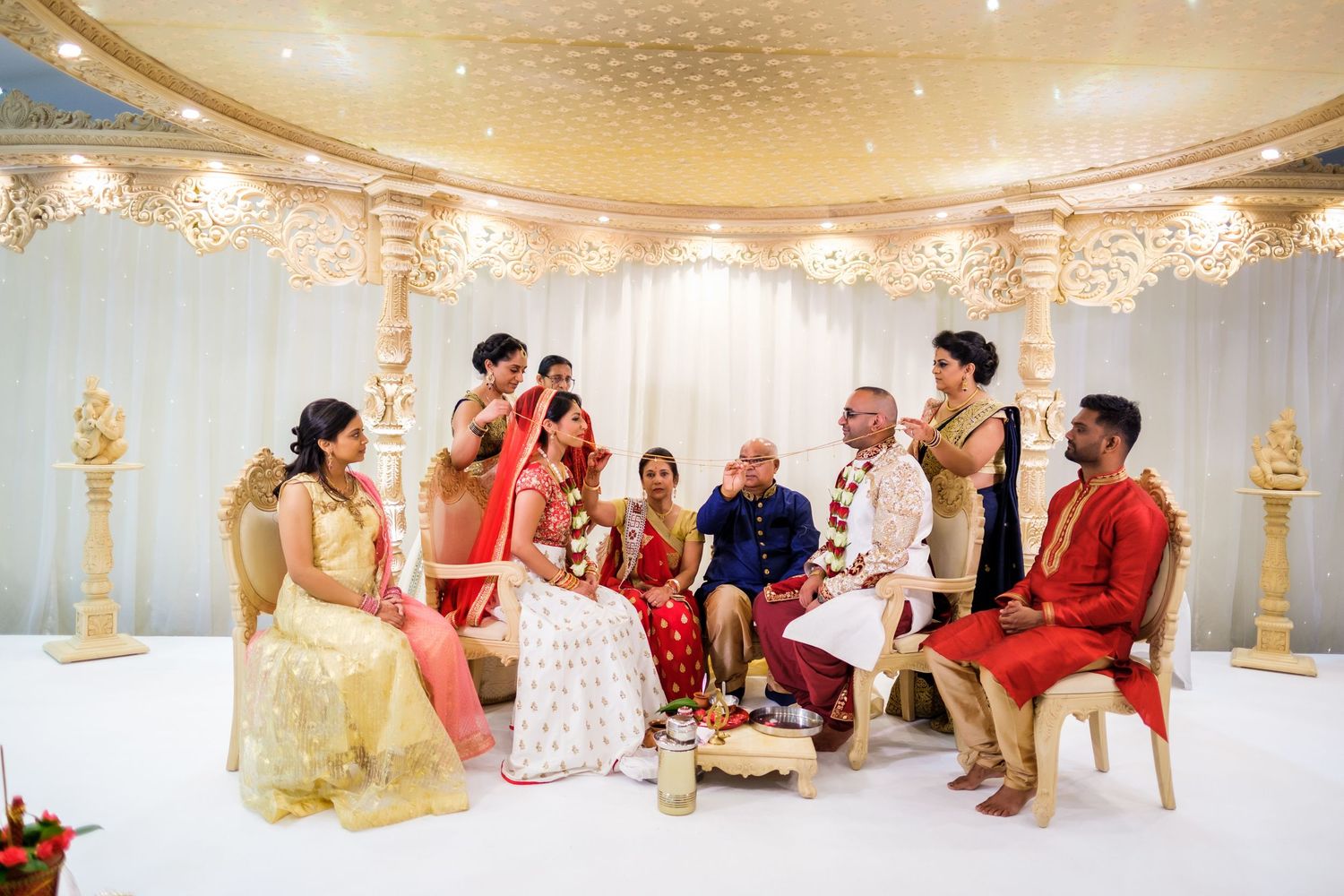 Elegant Indian wedding ceremony setup with gold decor and crystal chandeliers in a luxurious banquet hall.