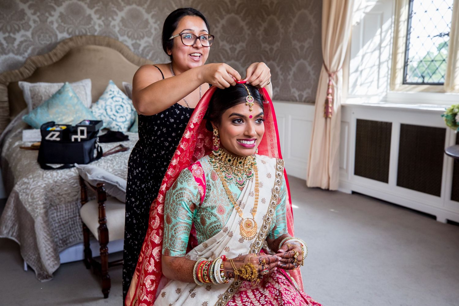 Traditional Indian bridal preparation scene with colorful saris and jewelry in an elegant room.