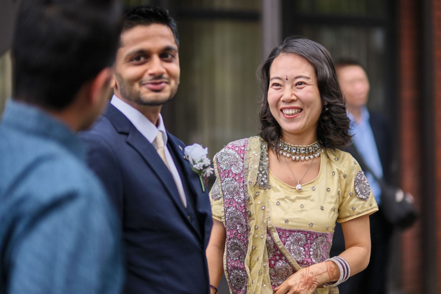 A group of guests mingle and socialize at an elegant formal event wearing traditional Indian attire.