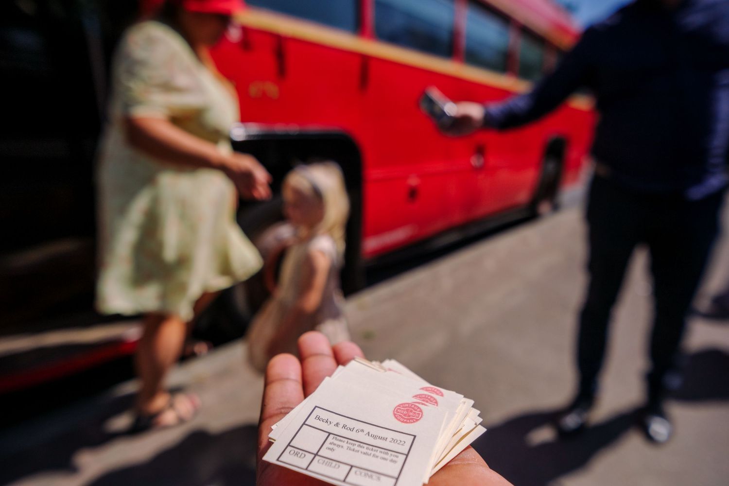 Close-up of hands holding playing cards during a card game on a red table surface.
