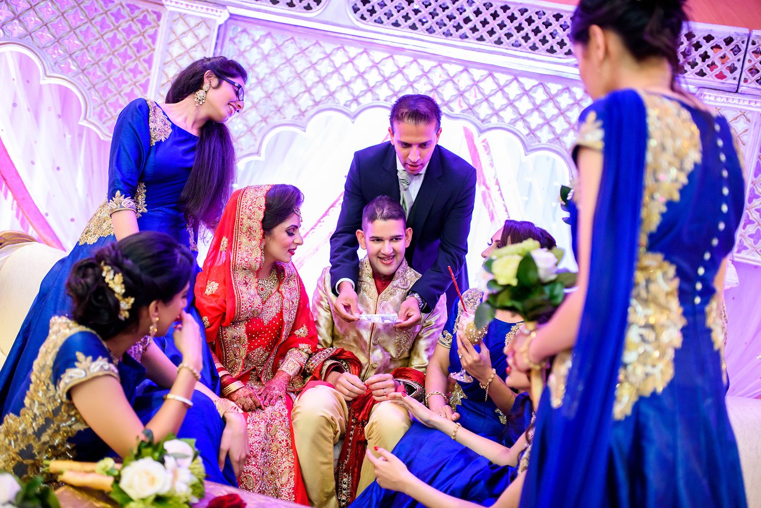 Guests celebrating and dancing at a colorfully lit wedding reception with purple and blue lighting effects.