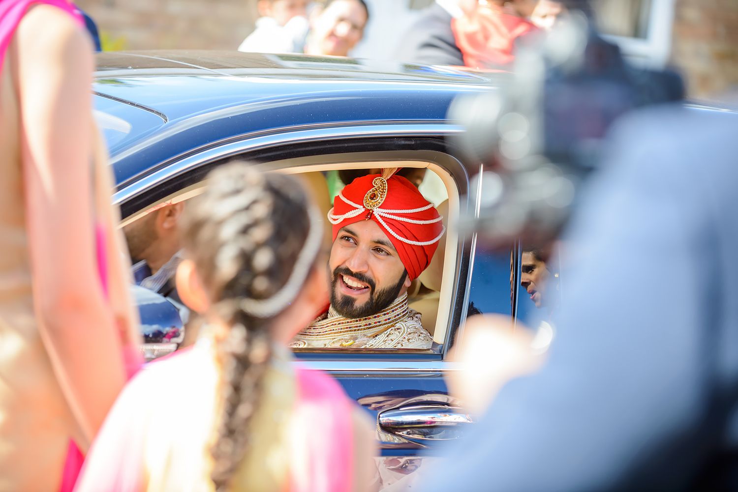 Wedding procession vehicles decorated with red flowers and ribbons.