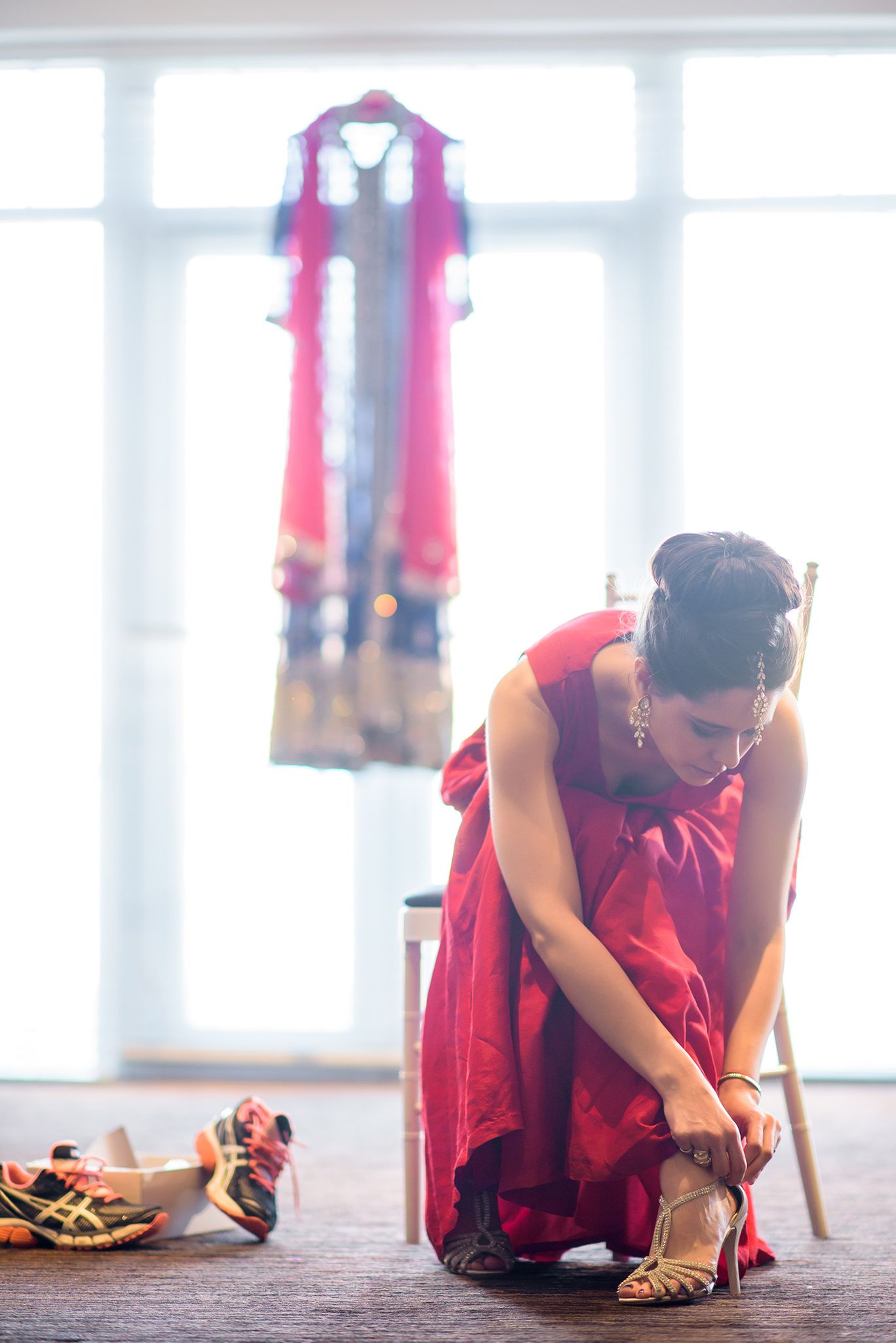 Wedding preparation scene with vibrant red traditional Indian outfits.