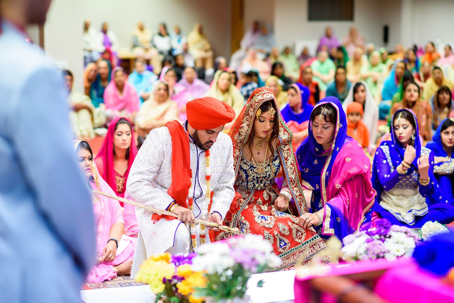 Colorful gathering of wedding guests seated during traditional Sikh ceremony.