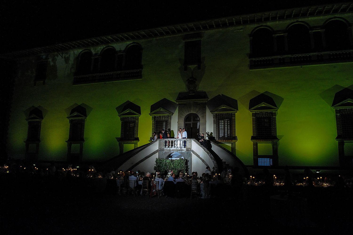Historic building facade illuminated with green lighting and grand staircase for evening event.