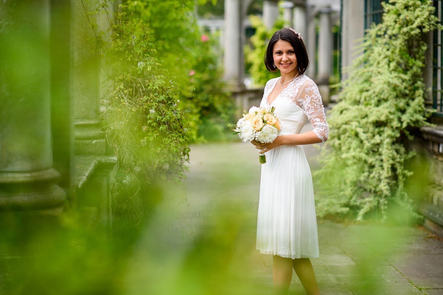 Garden pathway with classic white columns and verdant landscaping creates romantic atmosphere.