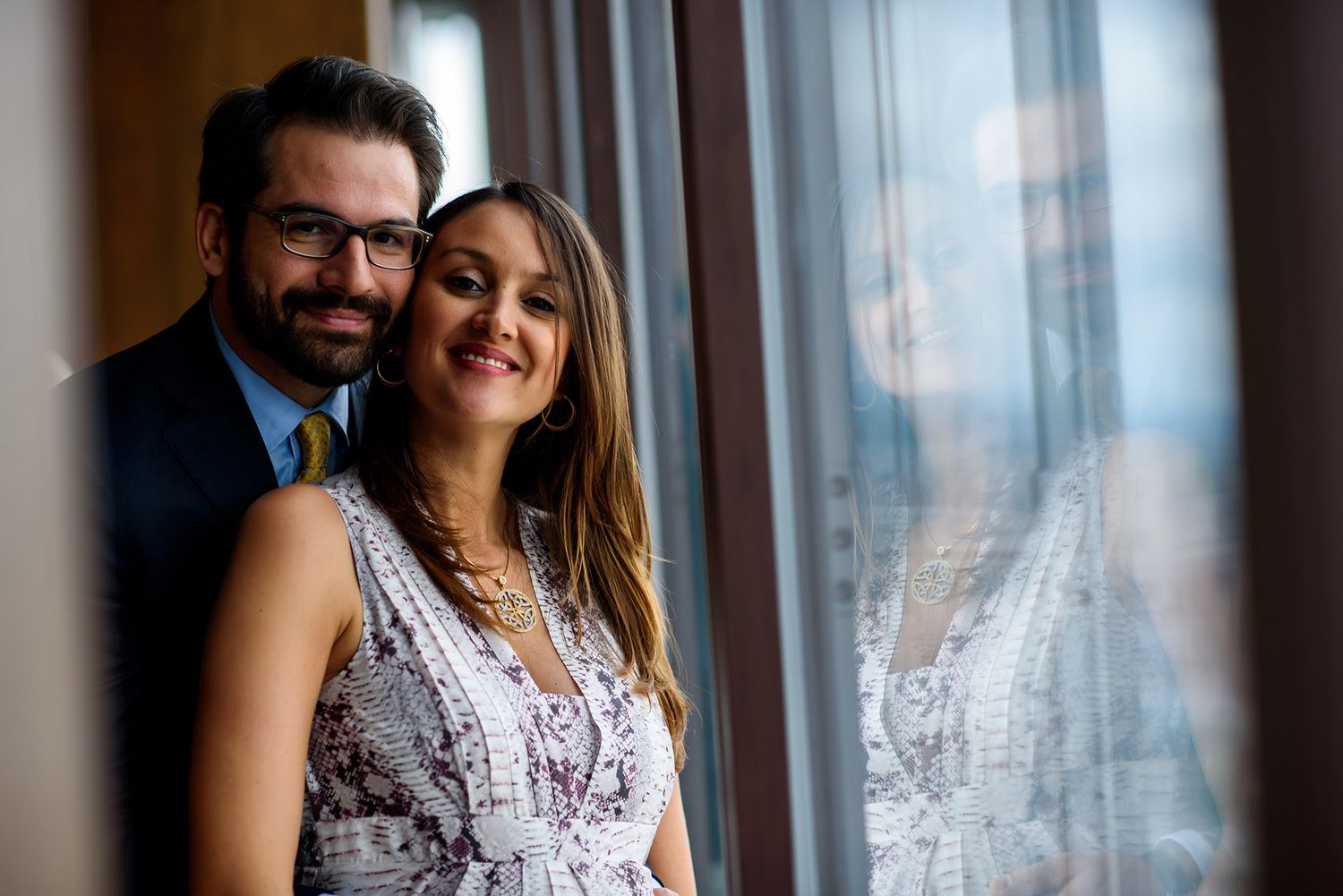 Romantic moment captured against panoramic city windows in natural light.