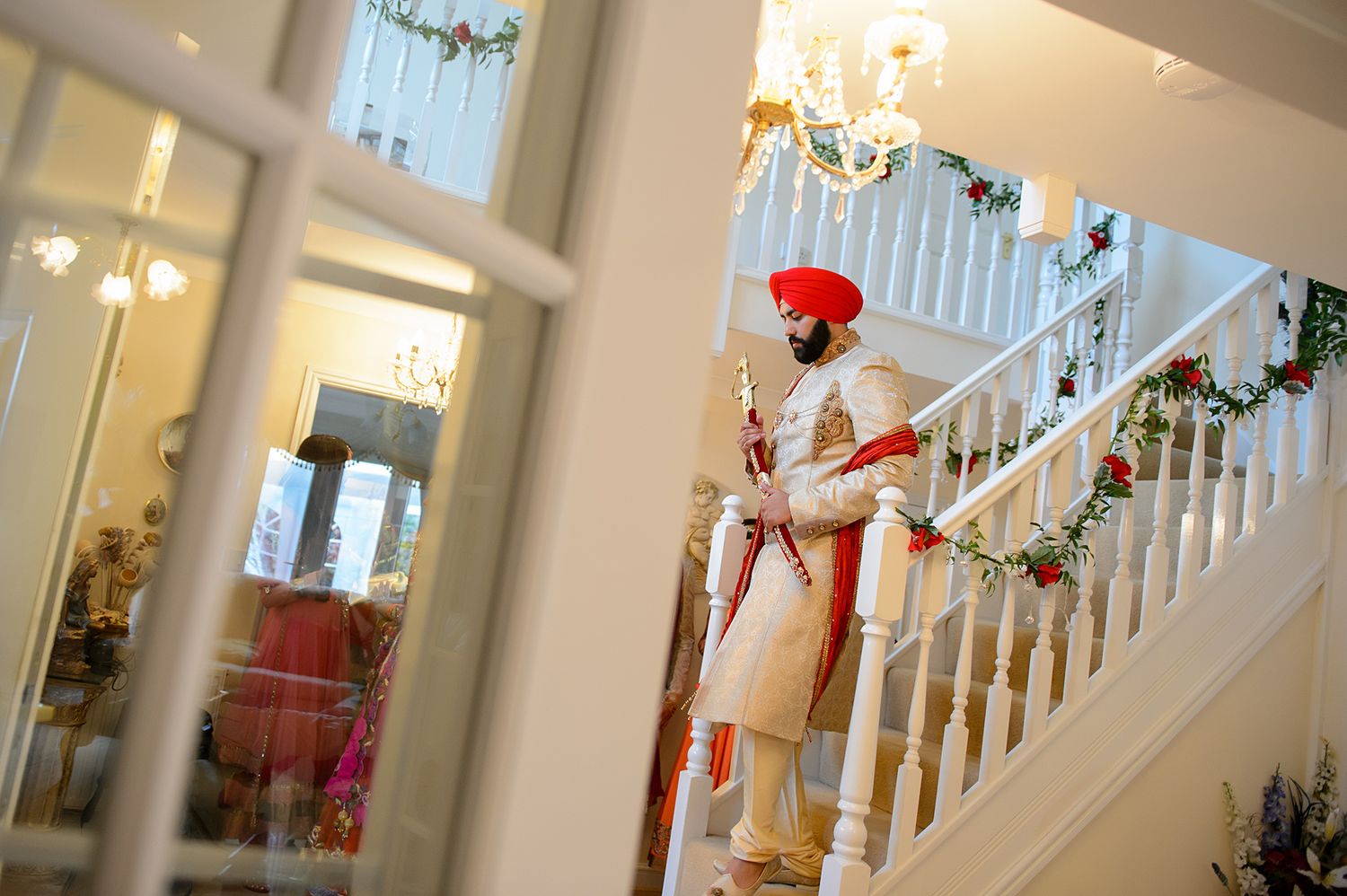 Elegant white staircase decorated with holiday garlands and red accents.