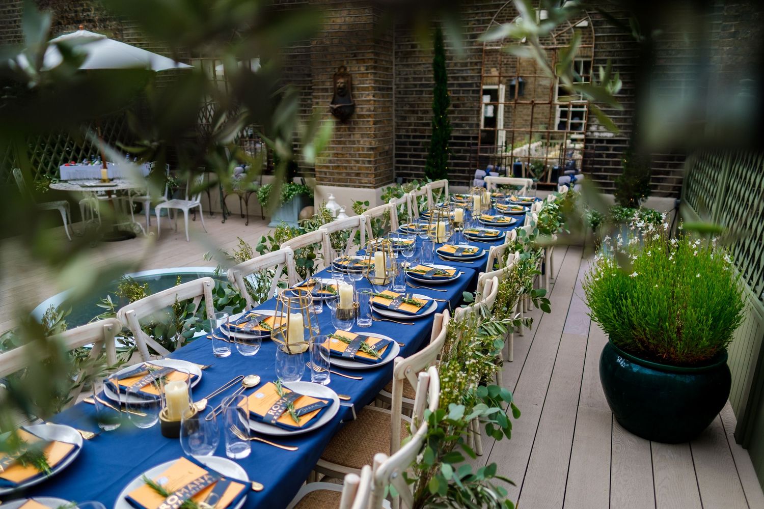 Elegant outdoor dining setup with blue tablecloths and place settings.