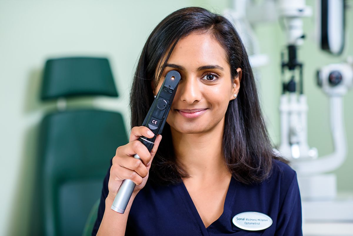 Healthcare professional in a navy scrub uniform poses with a medical device in a clinical setting.