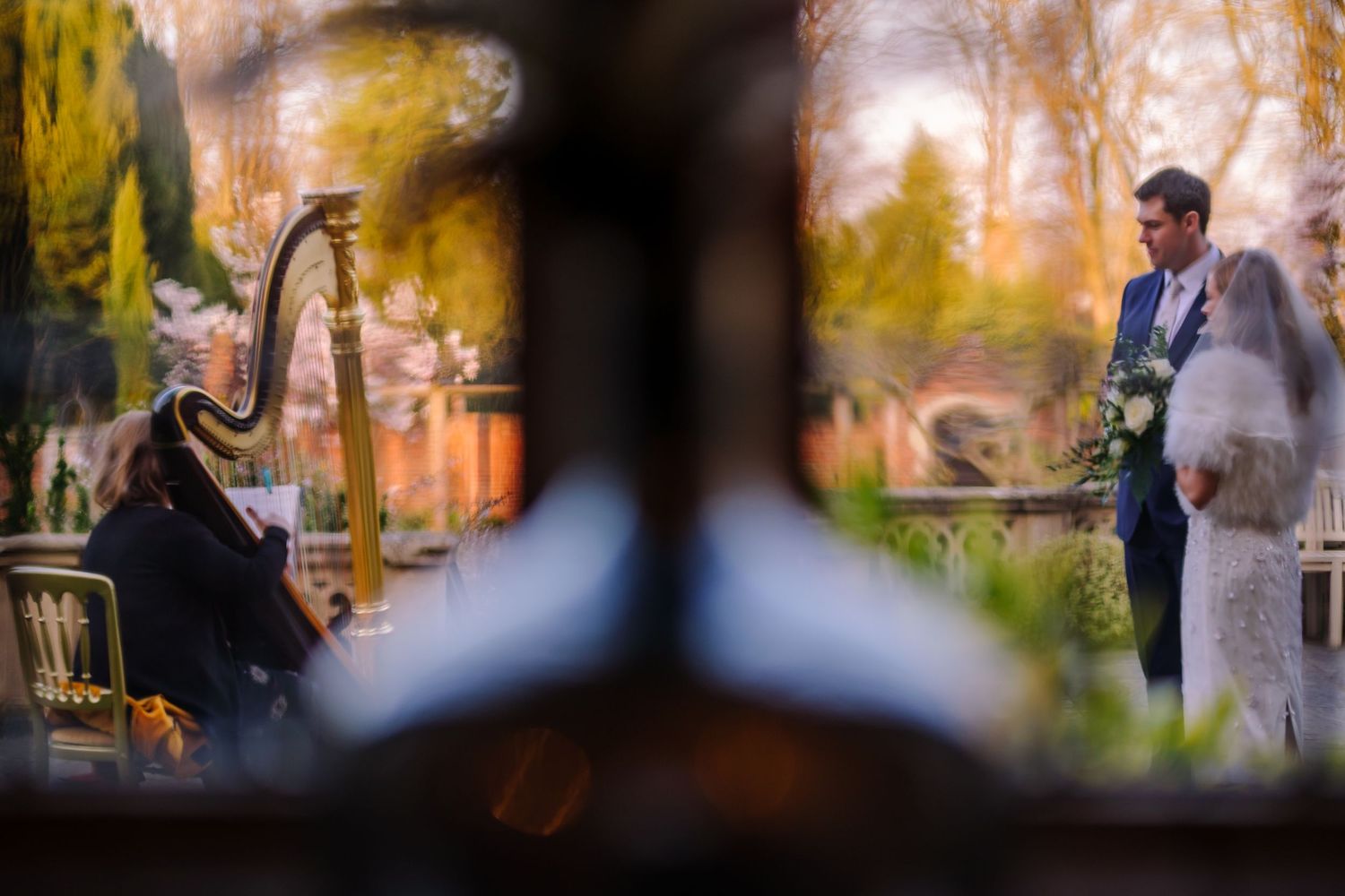 Autumn wedding ceremony photographs taken through foliage with golden sunlight filtering through.