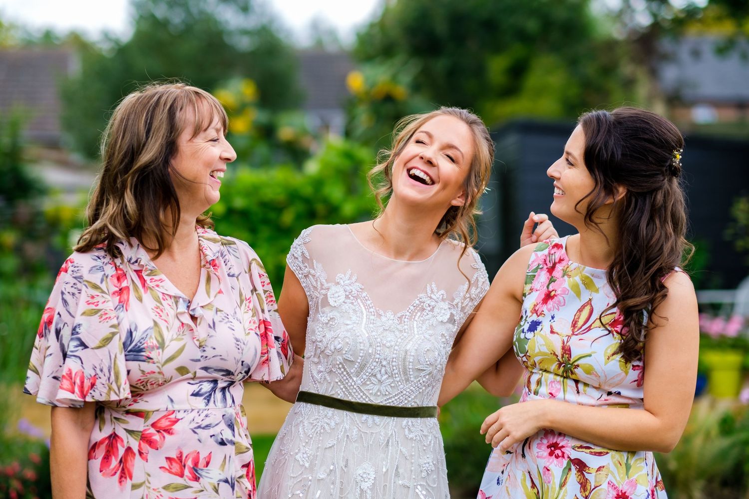 Bridesmaids in floral dresses share joyful moments together outdoors.