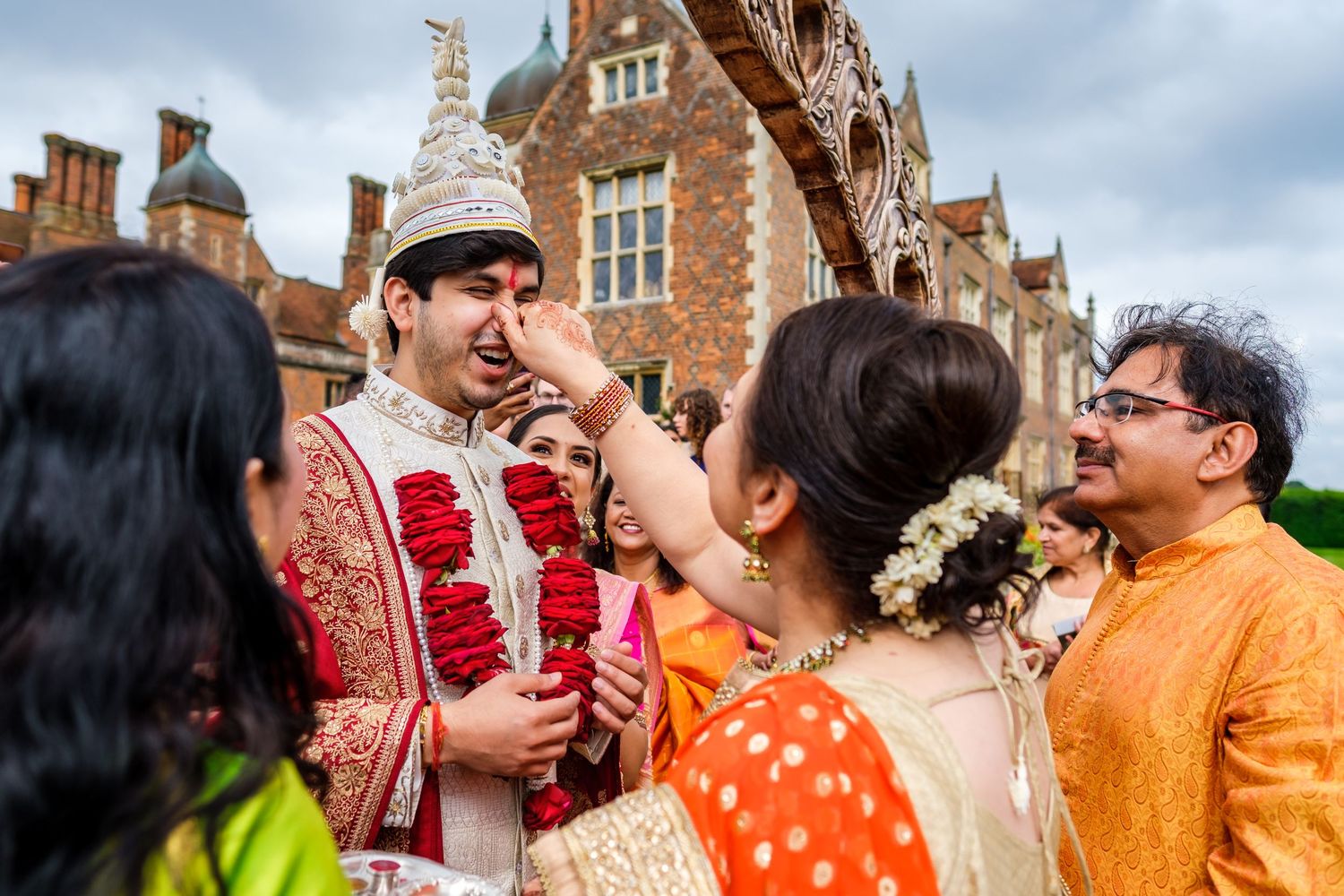 Wedding ceremony taking place outside historic brick building with traditional Indian attire.