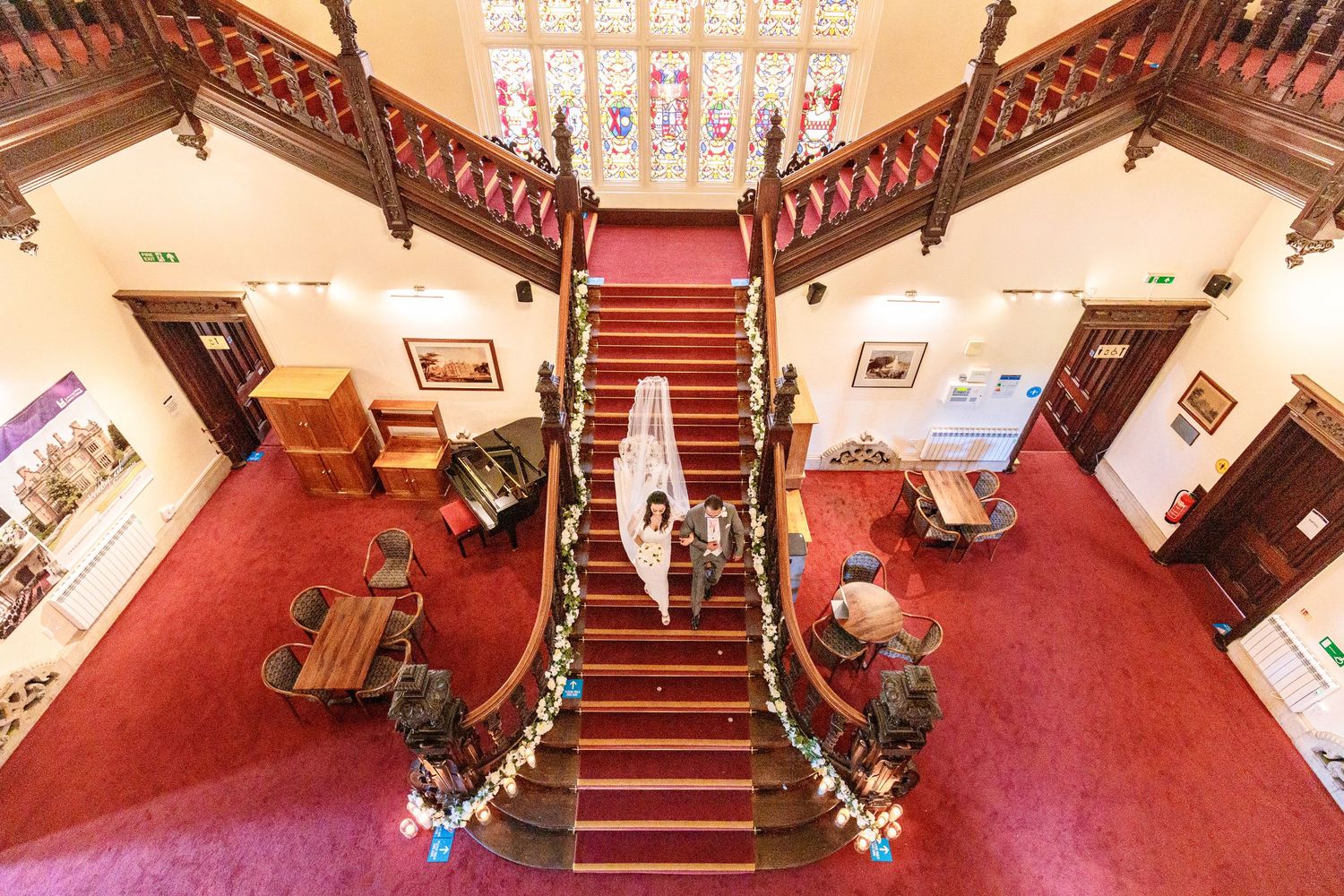 Red carpeted staircase with decorative railings in a historic wedding venue.