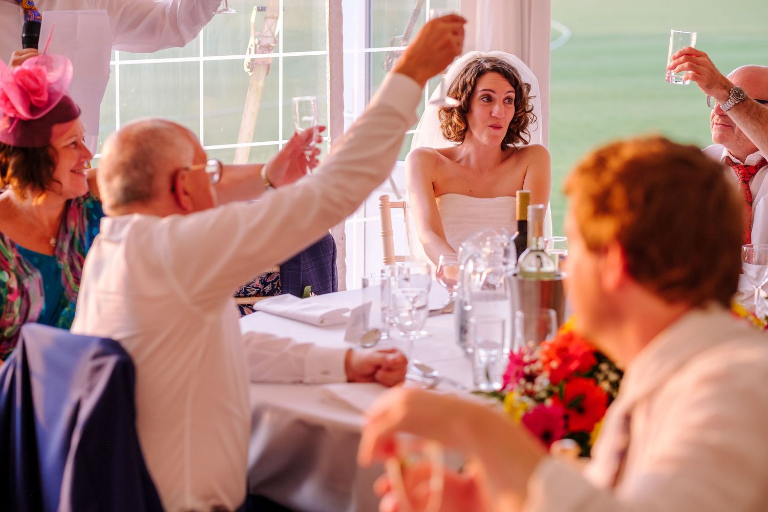 Wedding guests dancing and celebrating at a lively indoor reception with colorful lighting.