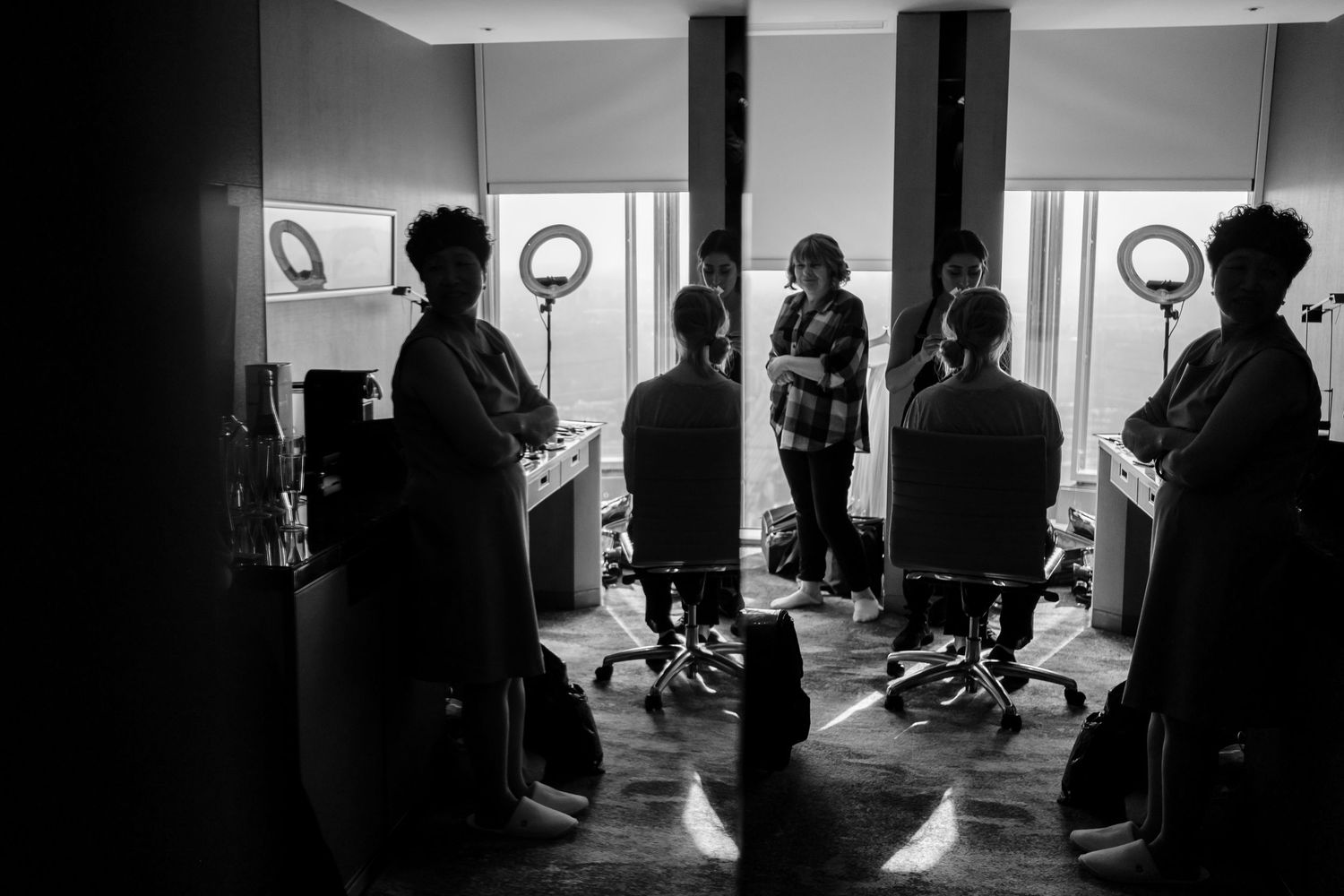 Silhouettes of people gathered in a salon with round porthole windows creating dramatic backlighting.