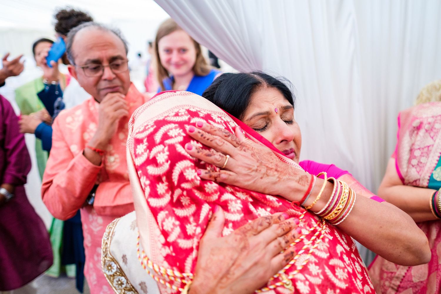 Close-up of hands adorned with traditional Indian bridal jewelry and henna designs.