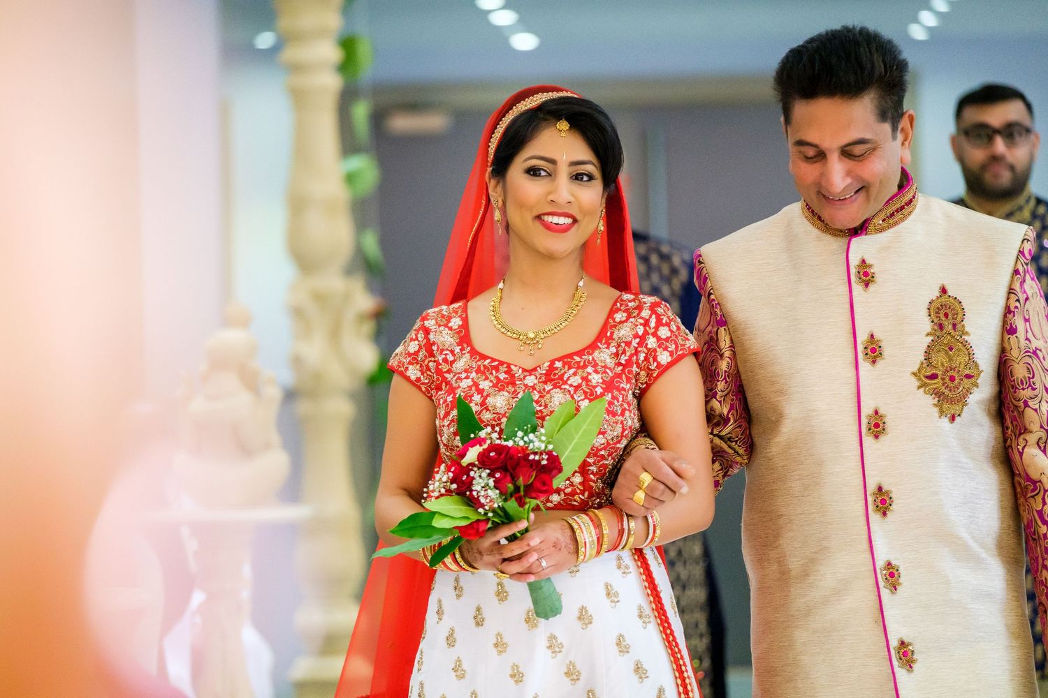 Colorful wedding celebration with traditional Indian attire and decorations at an indoor venue.