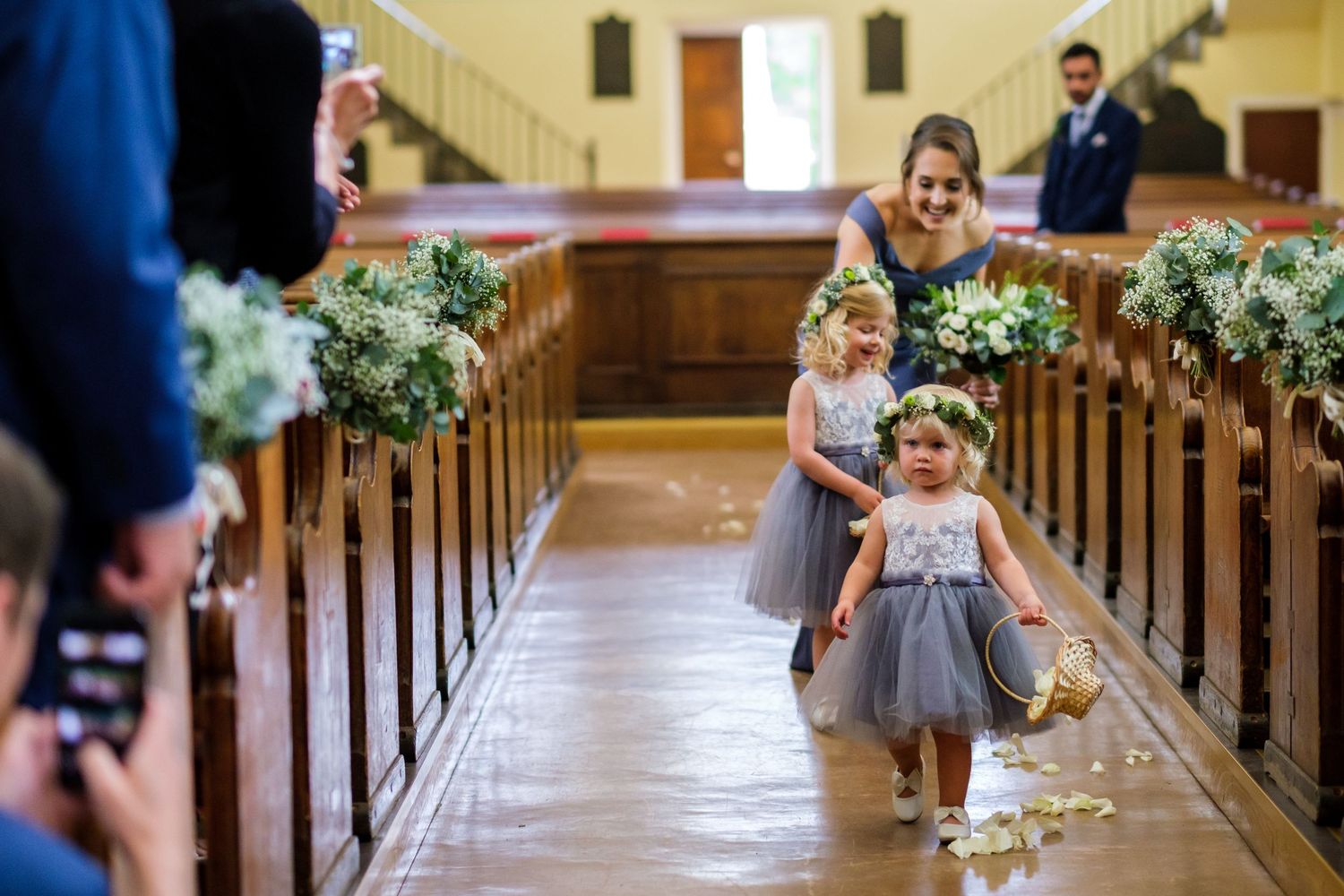 Wedding ceremony in a church with floral decorations along the pews.
