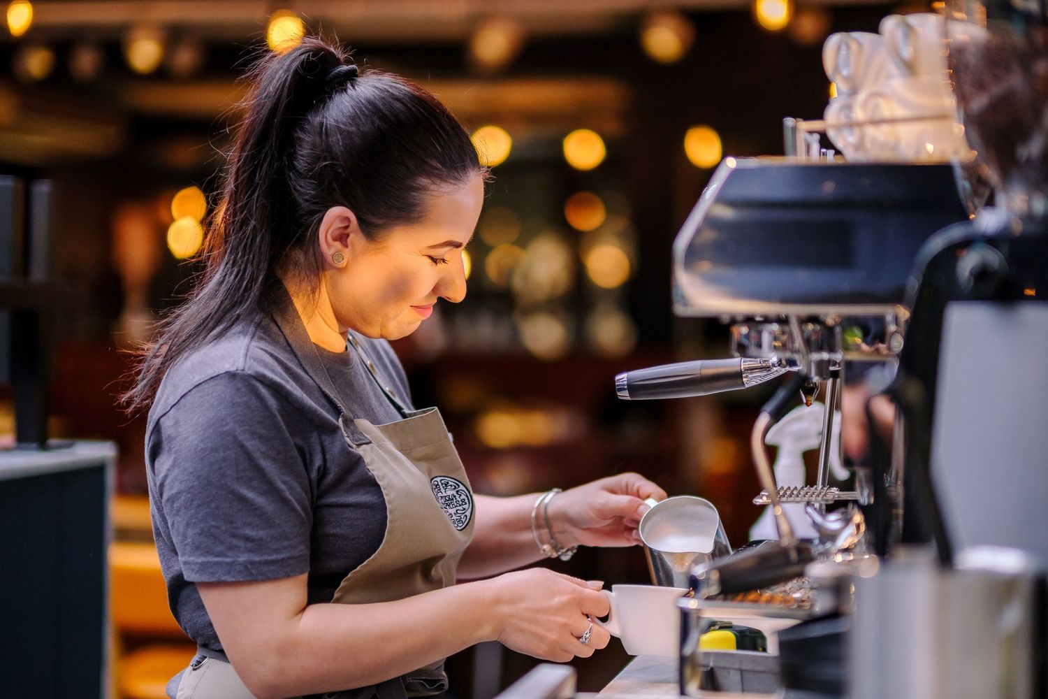 Restaurant staff preparing drinks and coffee behind counter with warm lighting.