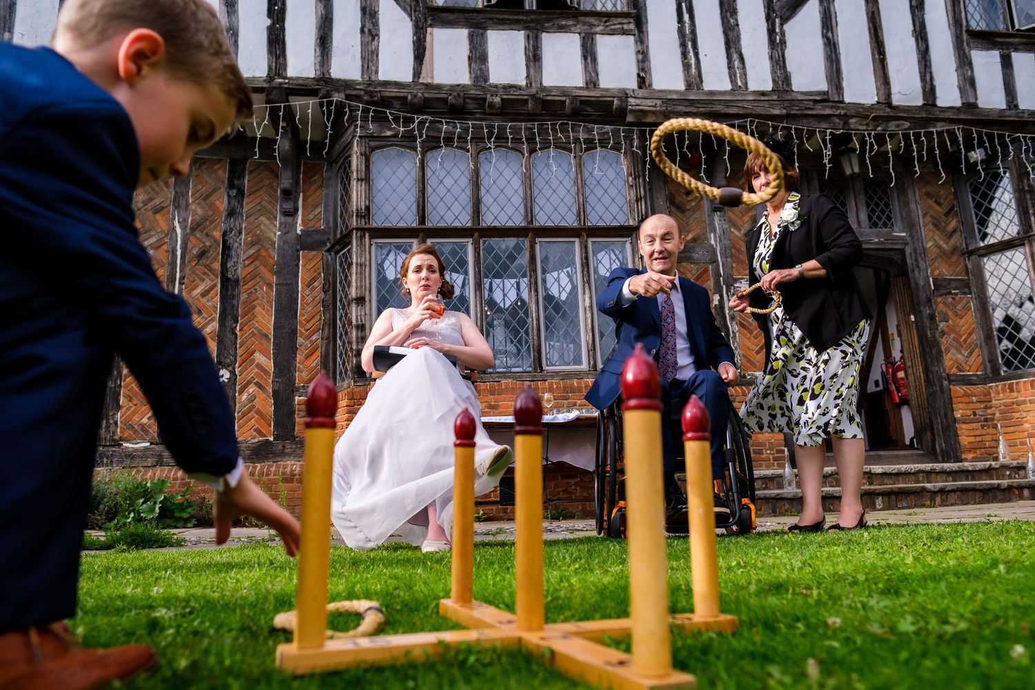 Children playing outdoor lawn games with yellow posts during a wedding reception.